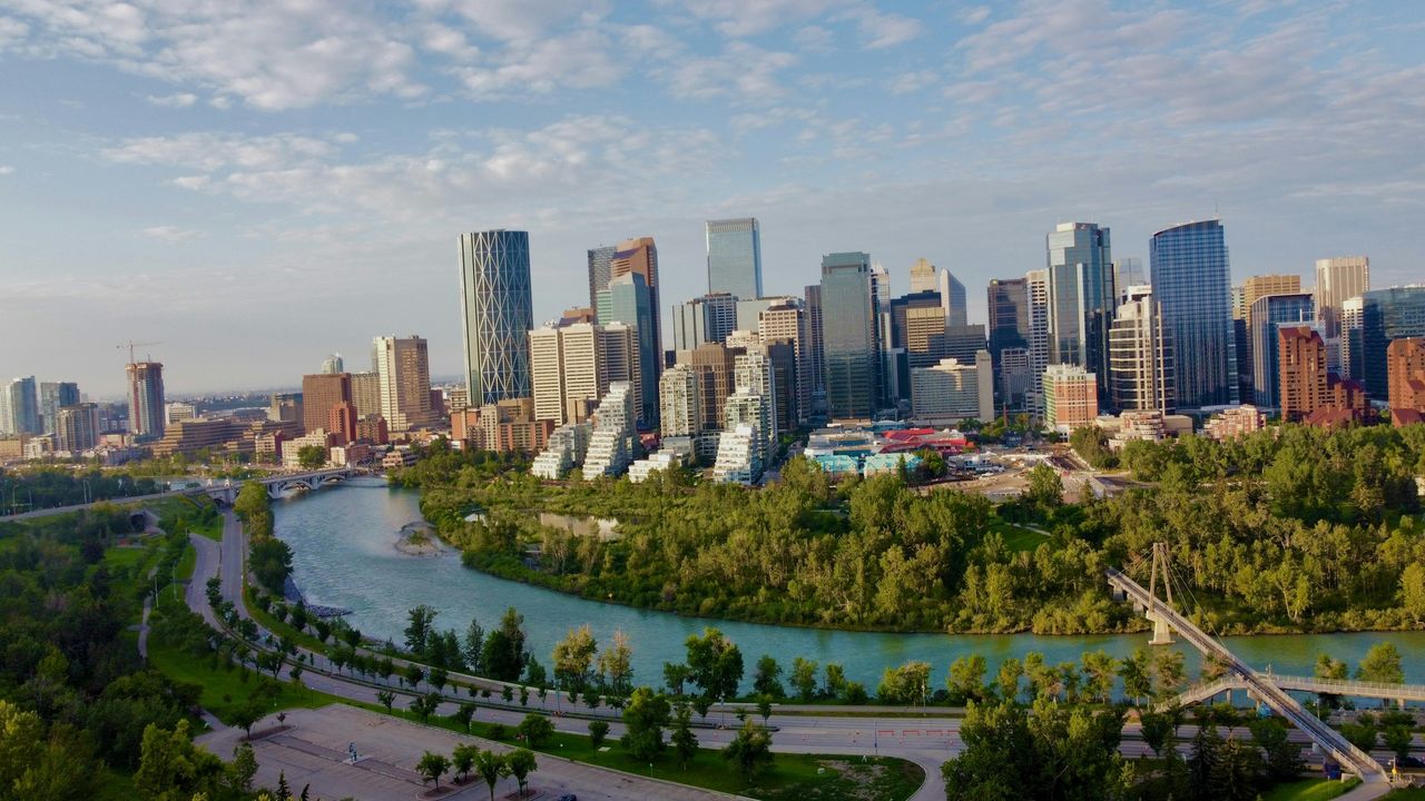 The Calgary skyline above the Bow River and its green pathways in summer.